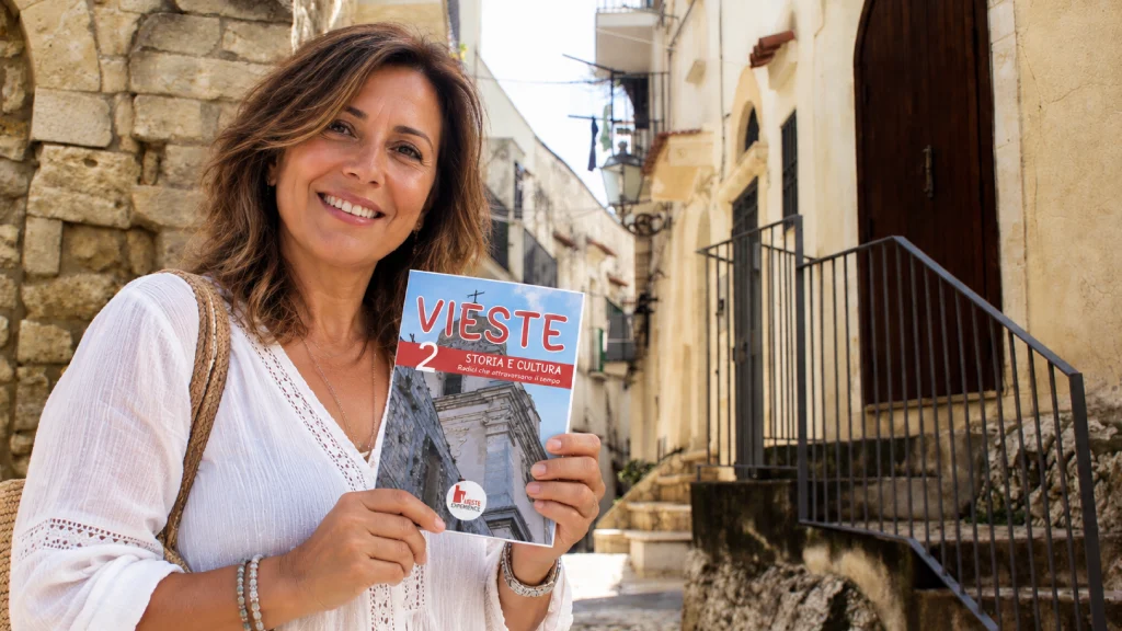 Una turista a Vieste Vecchia con in mano la guida N.2 di Vieste Experience, Storia e Cultura di Vieste