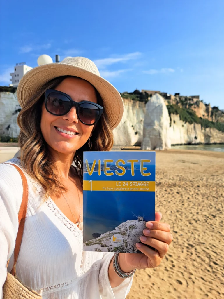turista a Vieste con in mano la guida n.1 di Vieste Experience, le 24 spiagge di Vieste. Al Pizzomunno