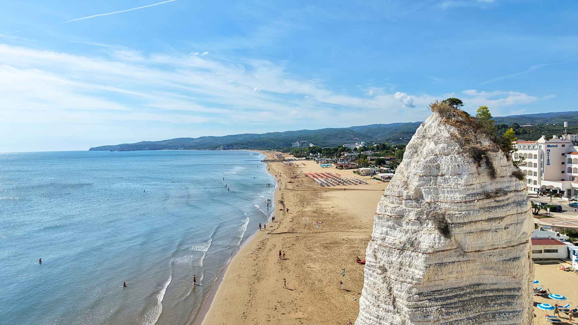 Il Pizzomunno di VIeste visto in primo piano a quasi 20 metri da terra, alle sue spalle la spiaggia della Scialara o del Castello, con le persone a riva